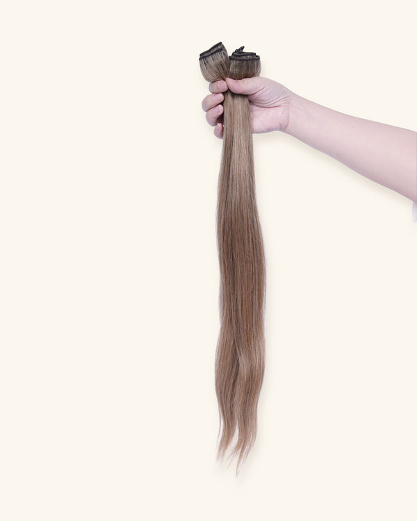 Set of 7 clip-in hair extensions, 22 inch blonde, held in hand
